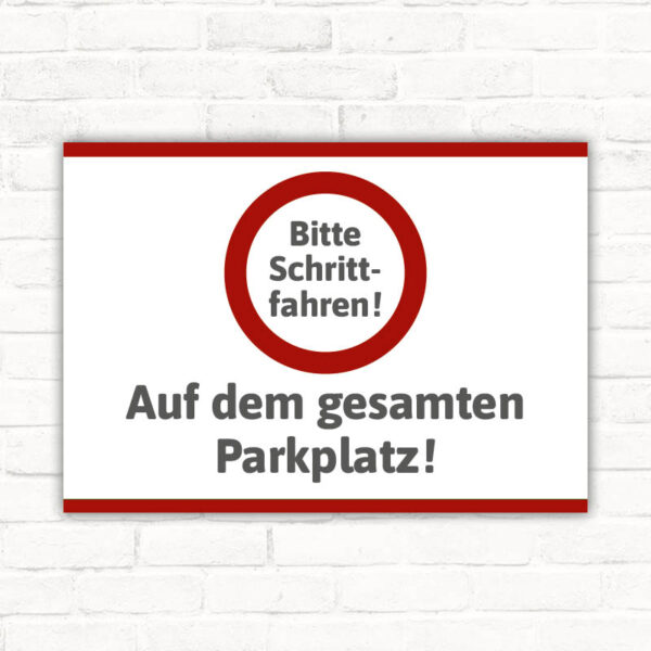 Schild Bitte Schrittfahren auf dem gesamten Parkplatz