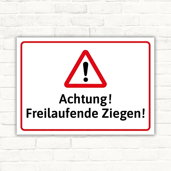 Warnschild mit dem Text „Achtung! Freilaufende Ziegen!“ und rotem Warndreieck