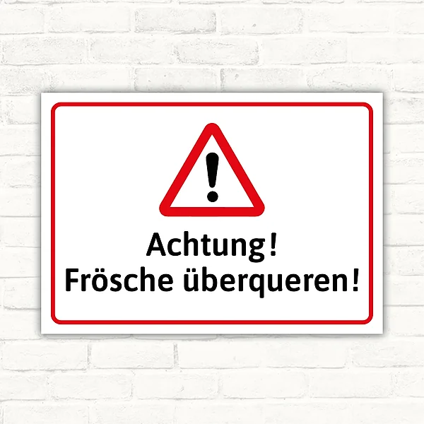 Warnschild mit Dreiecksymbol und Text „Achtung! Frösche überqueren!“ im Querformat