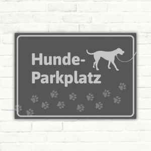 Grauer Schild mit Schriftzug Hunde-Parkplatz, Hundesilhouette und Pfotenmotiv.