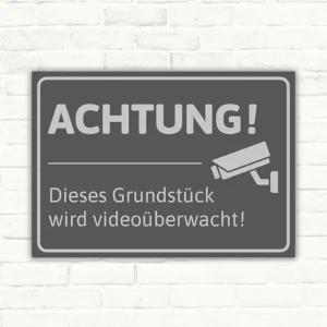 Schild mit dem Hinweis, dass ein Grundstück videoüberwacht wird, mit Kamera-Symbol.