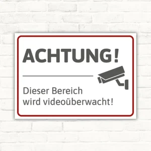 Schild mit Hinweis „Achtung! Dieser Bereich wird videoüberwacht“ und Kamerasymbol.