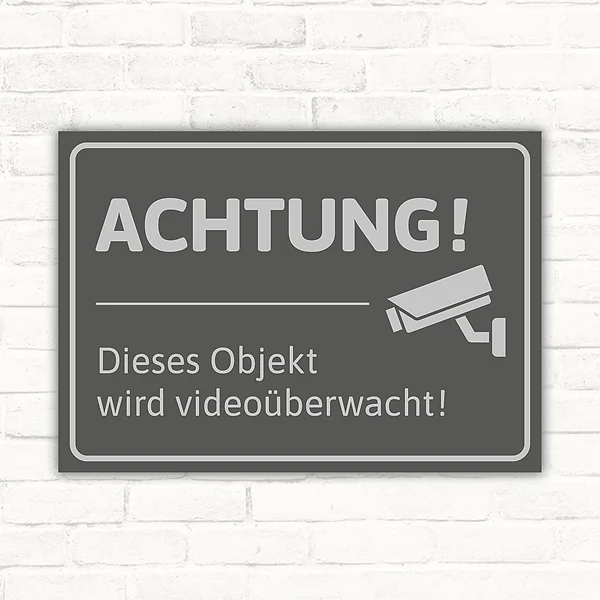 Schild mit dem Hinweis „Achtung! Dieses Objekt wird videoüberwacht“ und Kamerasymbol.
