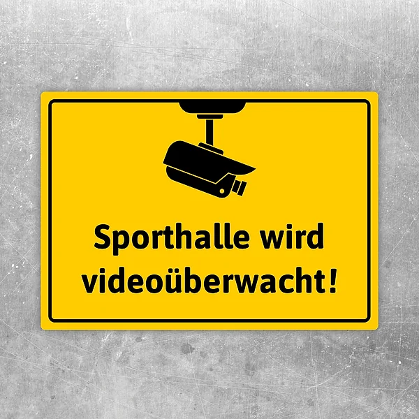 Gelber Aufkleber mit Kamerasymbol und dem Text: Sporthalle wird videoüberwacht.