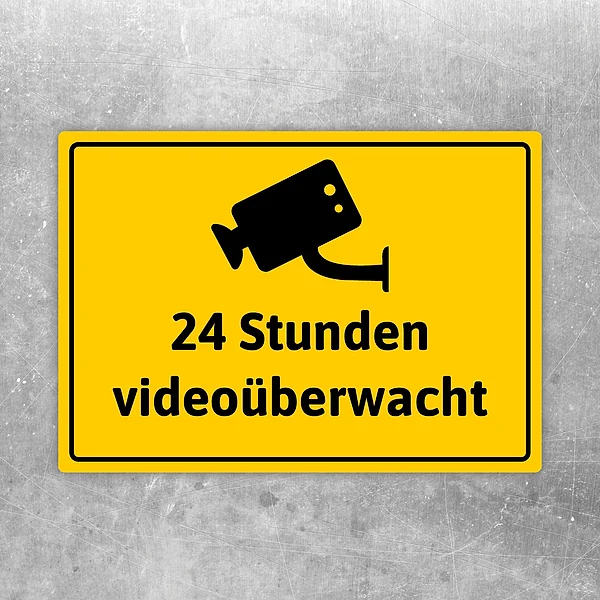 Gelber Aufkleber mit Kamerasymbol und dem Text 24 Stunden videoüberwacht.