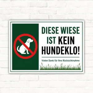 Hundeverbotsschild mit dem Text „Diese Wiese ist kein Hundeklo“ und Verbotssymbol auf weiß-grünem Schild.