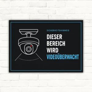 Videoüberwachungsschild mit Kamera-Symbol und dem Text „Dieser Bereich wird videoüberwacht“ auf schwarzem Hintergrund.