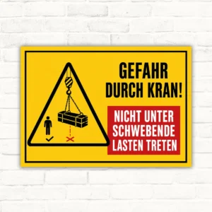Warnschild Gefahr durch Kran mit Hinweis „Nicht unter schwebende Lasten treten“ als gelbes Schild für den Arbeitsbereich.