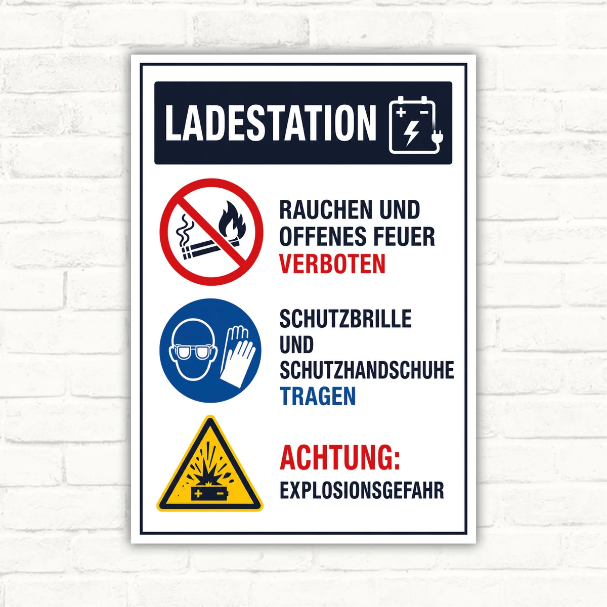 Bedrucktes Schild mit der Aufschrift „Ladestation“, Hinweisen zu Rauchverbot, Schutzkleidung und Explosionsgefahr im Hochformat.