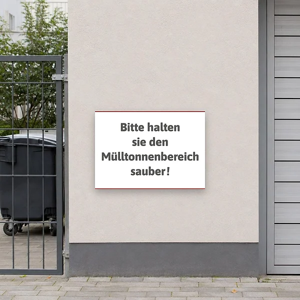 Hinweisschild an einer Hauswand neben dem Mülltonnenplatz, das Bewohner zu einem sauberen Abfallbereich auffordert.
