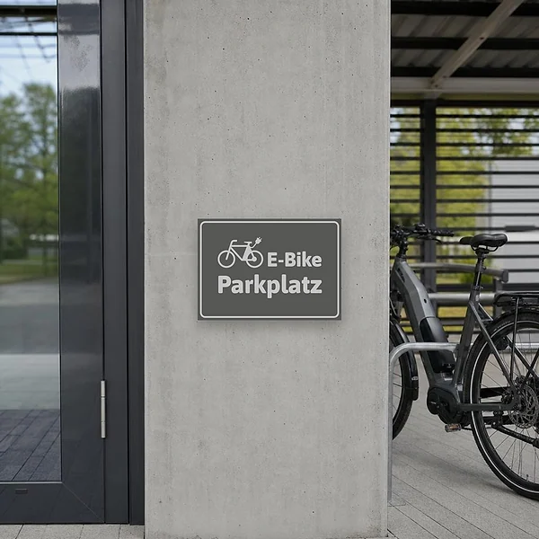 Grauer Hinweisschild für einen E-Bike-Parkplatz mit Fahrradicon und klarer Beschriftung.