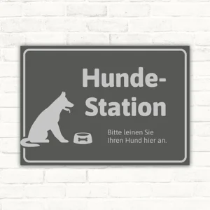 Grauer Schild Hundestation mit Hundesilhouette und Hinweis, den Hund hier anzuleinen.