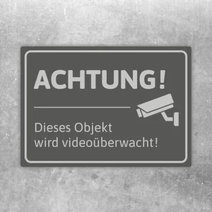 Aufkleber mit dem Hinweis „Achtung! Dieses Objekt wird videoüberwacht“ und Kamerasymbol.