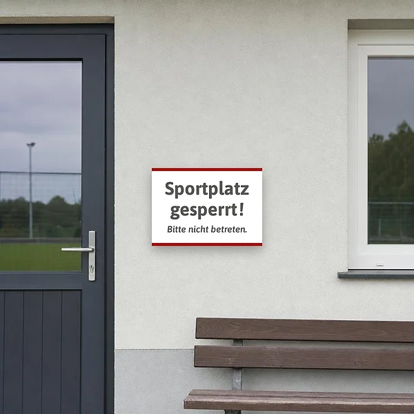Weißer Schild mit dem Text Sportplatz gesperrt und Bitte nicht betreten für den Zugang am Sportplatz.