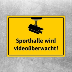 Gelber Aufkleber mit Kamerasymbol und dem Text: Sporthalle wird videoüberwacht.