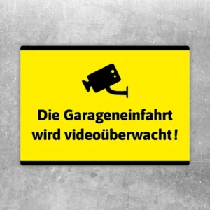 Gelber Aufkleber mit Kamerasymbol und dem Hinweis, dass die Garageneinfahrt videoüberwacht wird.