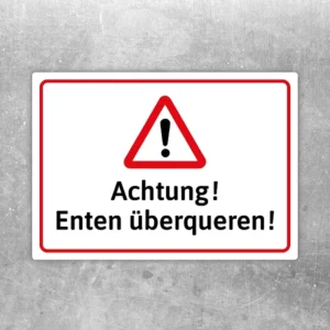 Warnaufkleber mit Dreiecksymbol und dem Text „Achtung! Enten überqueren!“ in Rot, Weiß und Schwarz.