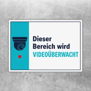 Querformatiger Videoüberwachung Aufkleber mit Kamera-Symbol und dem Text „Dieser Bereich wird videoüberwacht“ in Weiß, Türkis und Dunkelblau.
