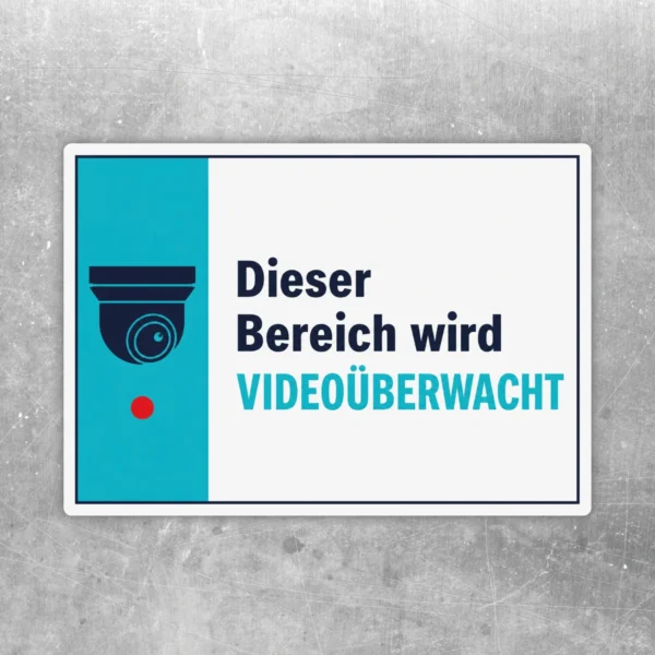 Querformatiger Videoüberwachung Aufkleber mit Kamera-Symbol und dem Text „Dieser Bereich wird videoüberwacht“ in Weiß, Türkis und Dunkelblau.