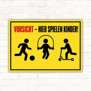 Vorsicht hier spielen Kinder Schild mit gelbem Hintergrund, spielenden Kindern und klarer Warnaufschrift als Schild für außen.