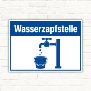 Bedrucktes Schild mit dem Text „Wasserzapfstelle“, blau-weißer Zapfhahn und Eimer, als Querformat-Hinweisschild.
