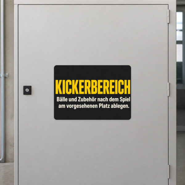 KI-generiertes Anwendungsbeispiel: Kickerbereich Aufkleber an grauer Fläche mit violettem Schriftzug und Tischkicker-Motiv.