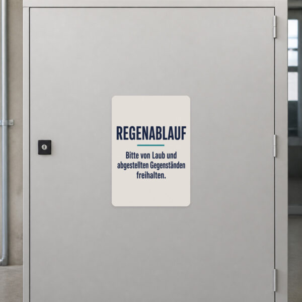 KI-generiertes Anwendungsbeispiel: Regenablauf freihalten Aufkleber an grauer Fläche mit Hofmotiv und Laubhinweis.
