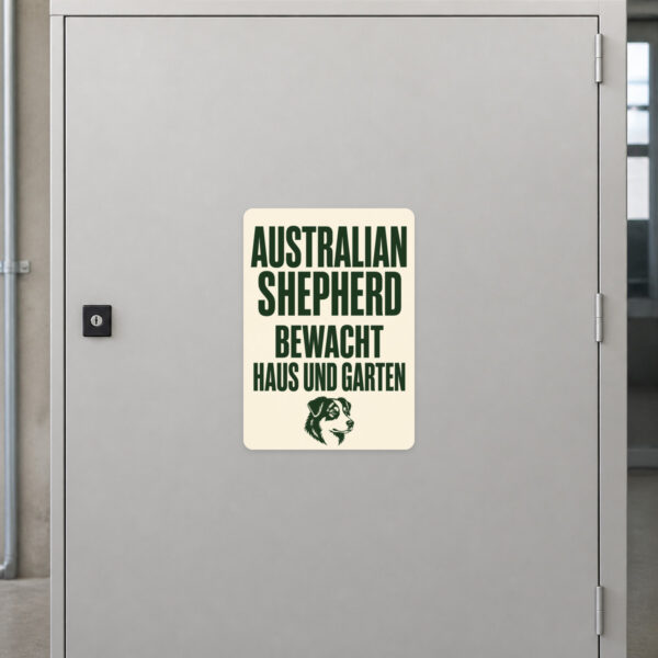 KI-generiertes Anwendungsbeispiel: Australian Shepherd Aufkleber an grauer Fläche mit Warntext für Haus und Garten.