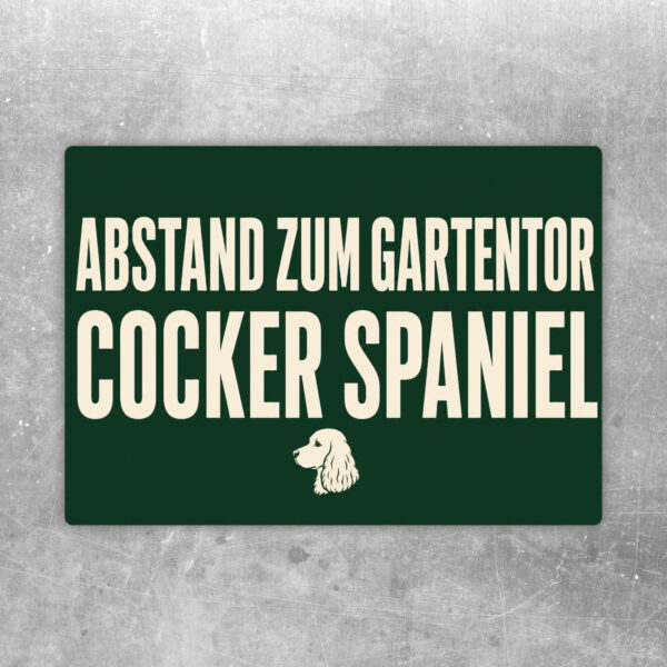 Cocker Spaniel Aufkleber im Querformat mit Text Achtung Bitte Abstand zum Gartentor halten in Rot, Blau und Weiß.