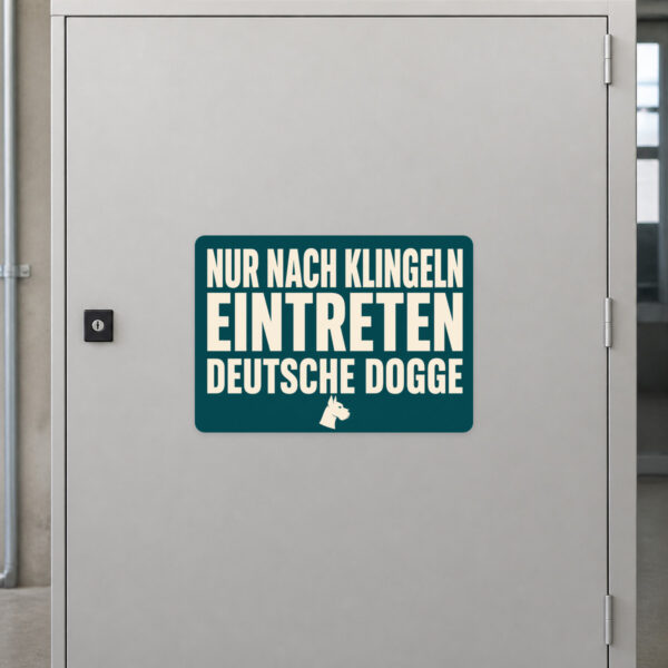 KI-generiertes Anwendungsbeispiel: Aufkleber Deutsche Dogge mit Vorsicht-Hinweis an grauer Oberfläche im Querformat.
