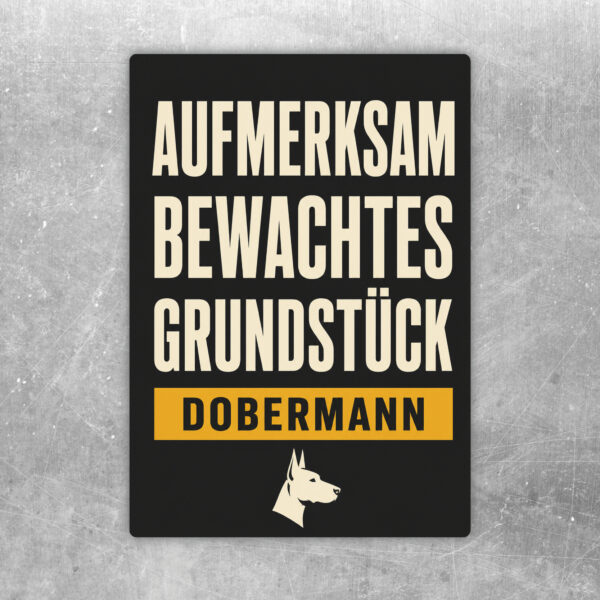 Aufkleber mit Dobermann, Text Achtung aufmerksam bewachtes Grundstück, schwarz-beige-braunes Warnmotiv.