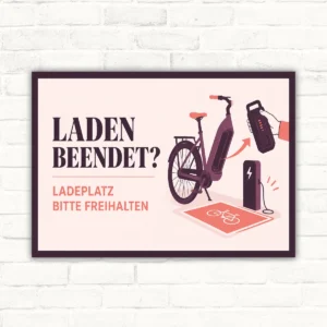 Querformatiges Schild mit E-Bike und Ladesäule, Text „Laden beendet? Ladeplatz bitte freihalten“.