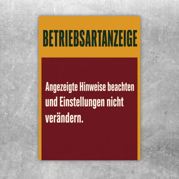 Betriebsartanzeige Aufkleber mit Hinweistext auf beigem Grund, grüner und oranger Grafik für technische Bedienplätze.