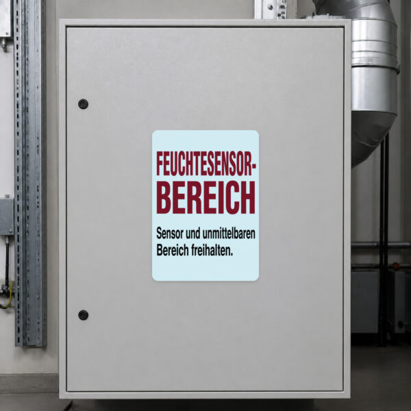 KI-generiertes Anwendungsbeispiel: Feuchtesensor Bereich freihalten Aufkleber auf grauer Technikfläche.