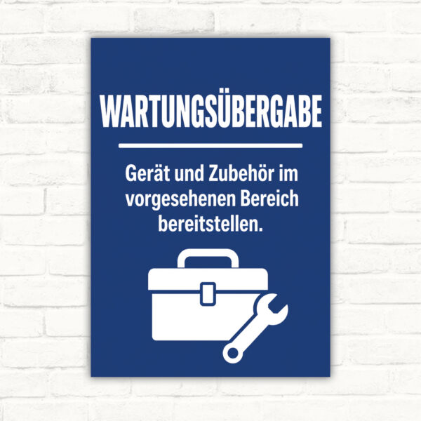 Wartungsübergabe Schild mit Text „Gerät und Zubehör im vorgesehenen Bereich bereitstellen“ und technischem Motiv.