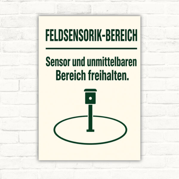 Feldsensorik-Bereich Schild mit Wortlaut „Sensor und unmittelbaren Bereich freihalten“ und Sensor im Feld.