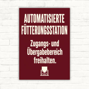 Schild „Automatisierte Fütterungsstation – Zugangs- und Übergabebereich freihalten“ mit Hoftechnik-Motiv.