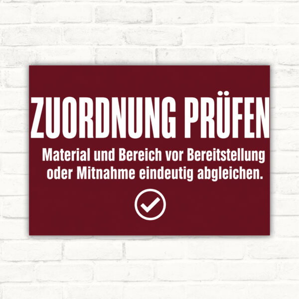 Zuordnung prüfen Schild mit Text „Material und Bereich vor Bereitstellung oder Mitnahme eindeutig abgleichen“ im Querformat.