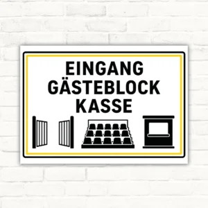 Hinweisschild mit der Aufschrift Eingang Gästeblock Kasse, schwarzer Text, gelber Rahmen und Piktogrammen als Türschild.