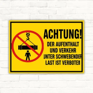 Verbotsschild mit gelbem Hintergrund: schwebende Last verboten, durchgestrichenes Lastsymbol und klarer Warntext im Querformat.