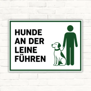 Hunde an der Leine führen Schild mit grünem Piktogramm von Person und Hund, bedrucktes Hinweisschild für den Außenbereich.
