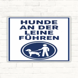 Hunde an der Leine führen Schild mit gut lesbarem Motiv und klarer Beschriftung als bedrucktes Schild aus Aluminium-Verbundplatte.
