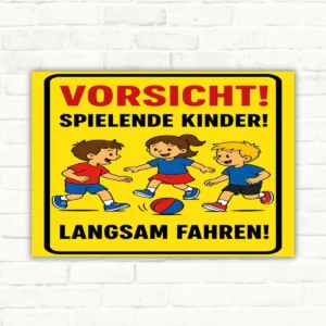 Gelbes Schild mit der Aufschrift „Vorsicht! Spielende Kinder! Langsam fahren!“ und drei spielenden Kindern.