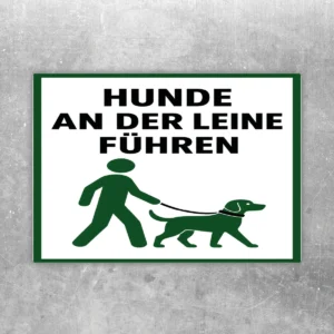 Aufkleber mit grünem Hundesymbol und Text „Hunde an der Leine führen“ auf weißem Hintergrund.