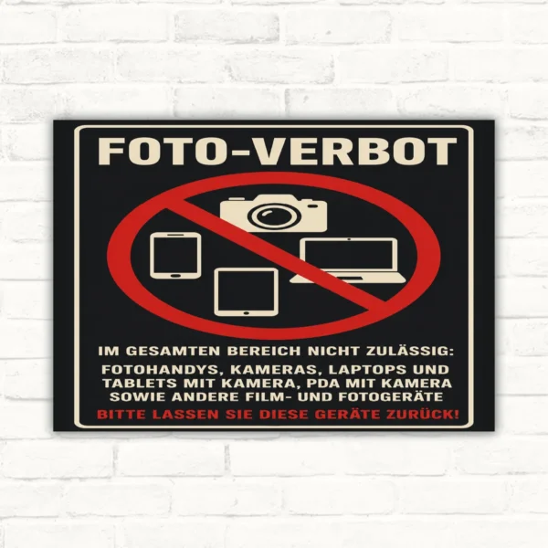 Foto-Verbotsschild mit Kamera-, Smartphone- und Laptop-Symbol sowie dem Text „Bitte lassen Sie diese Geräte zurück“.