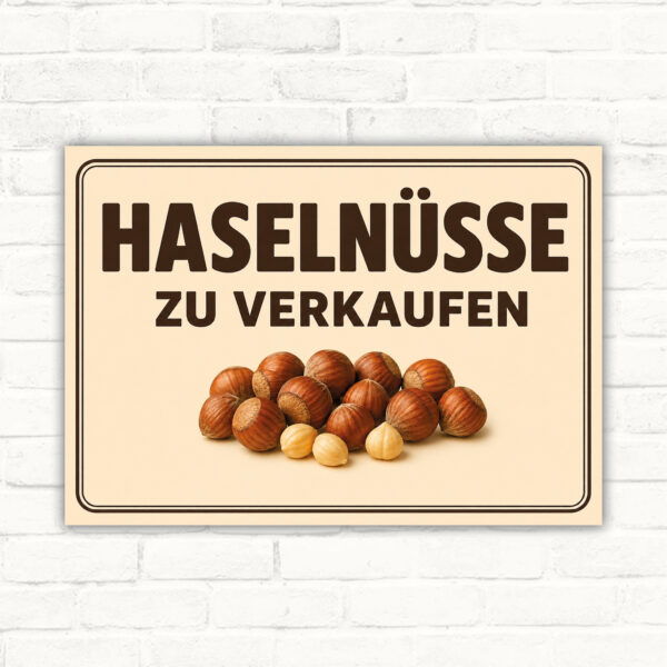 Schild mit Haselnüssen und dem Text „Haselnüsse zu verkaufen“ als Verkaufsschild im Querformat.