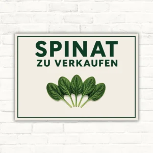 Spinat zu verkaufen Schild mit grünem Schriftzug, Spinatblättern und klarer Verkaufsbotschaft auf hellem Hintergrund.