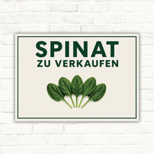 Spinat zu verkaufen Schild mit grünem Schriftzug, Spinatblättern und klarer Verkaufsbotschaft auf hellem Hintergrund.