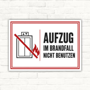 Aufzug im Brandfall nicht benutzen Schild mit rotem Verbotssymbol, Flammenmotiv und schwarzem Hinweistext im Querformat.