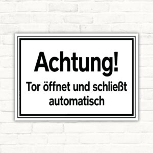 Warnschild mit Text „Achtung! Tor öffnet und schließt automatisch“ in Schwarz-Weiß für automatische Toranlagen.